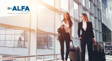 Dos mujeres ejecutivas con equipaje de viaje caminando 